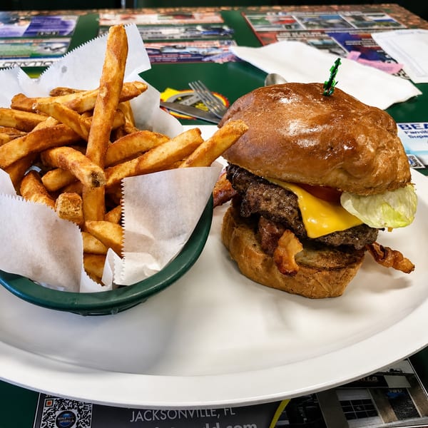 A double cheeseburger with bacon, lettuce, and cheese, served with a side of fries.